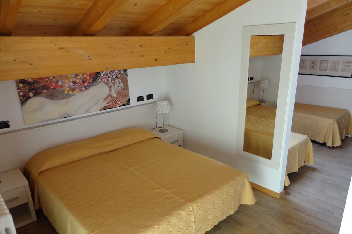 A bedroom with a bed, a nightstand, a lamp, a mirror, and a painting on the wall.