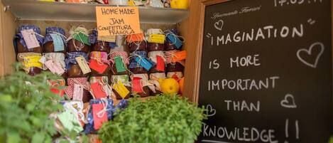 A display of homemade jam jars with colorful labels, a chalkboard with motivational writing, and a potted plant.