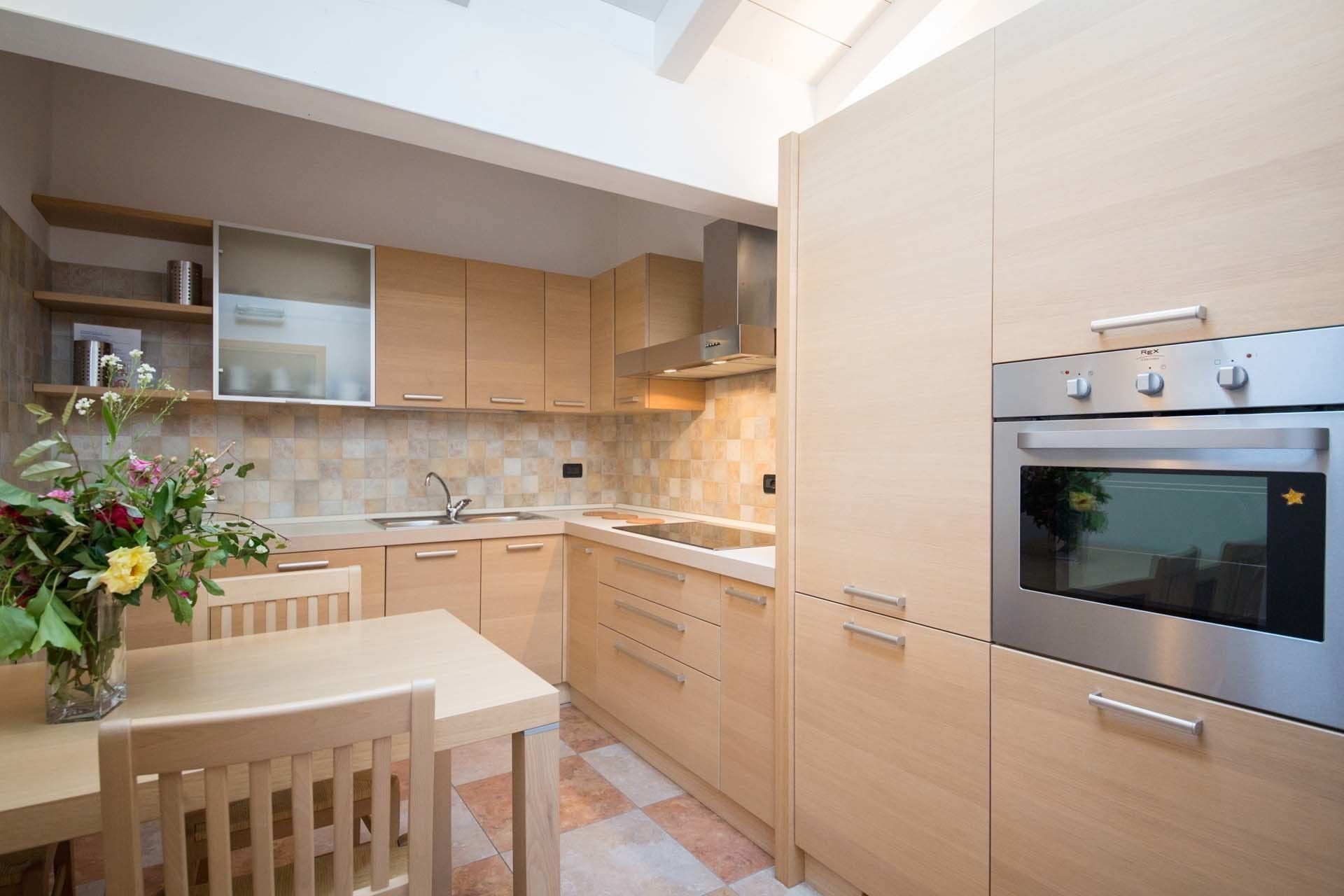 A modern kitchen with wooden cabinets, a stainless steel oven, and a tiled backsplash.