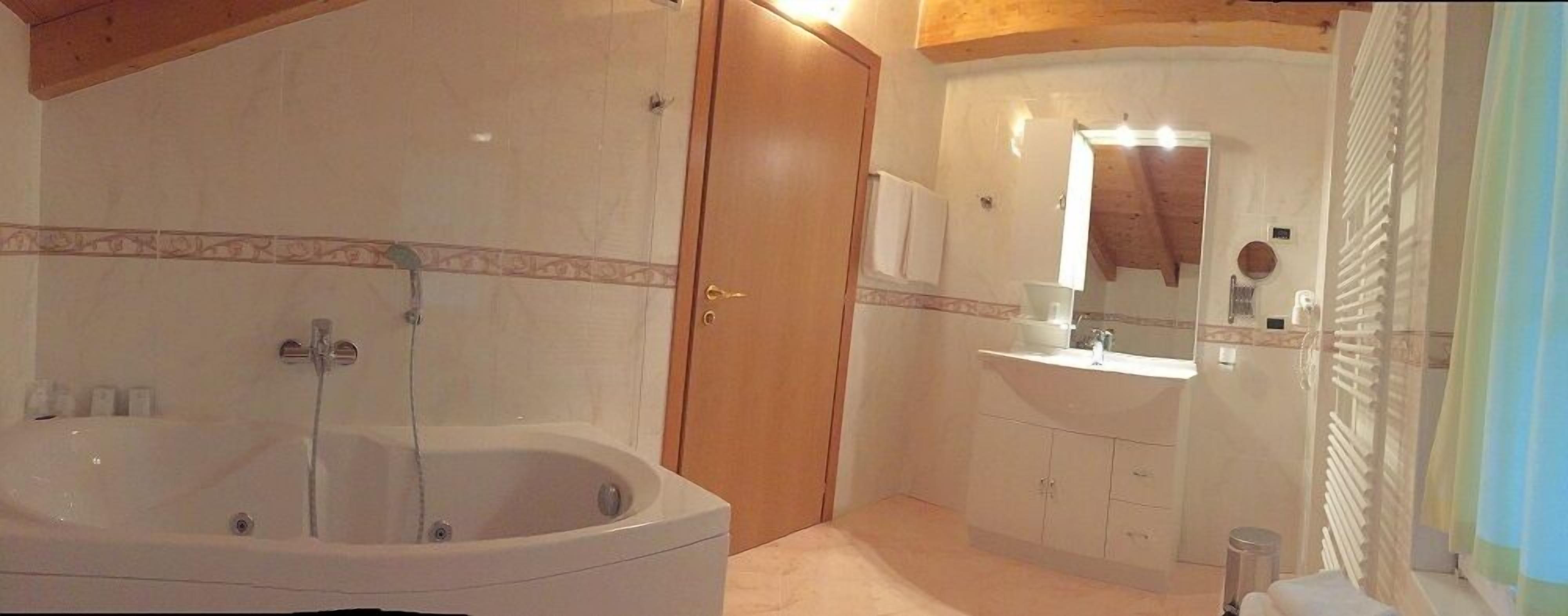 A bathroom with a bathtub, a sink, and a mirror.