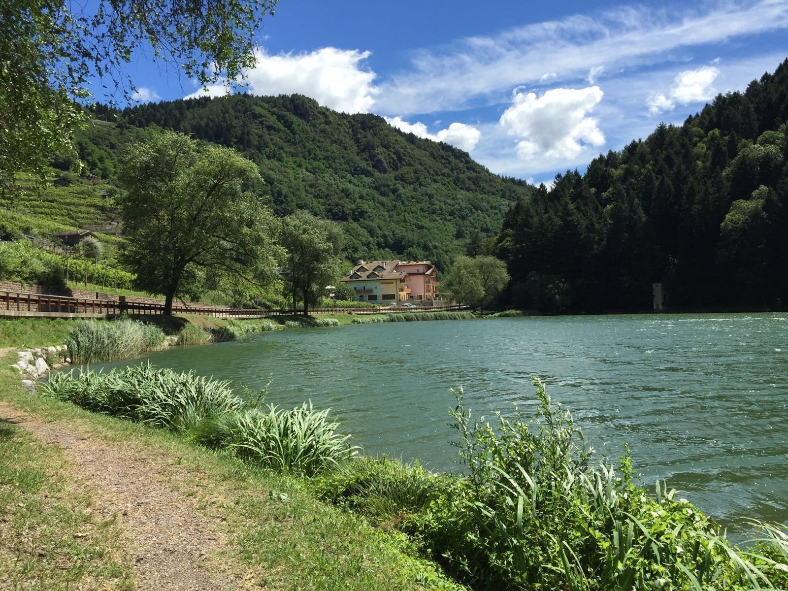 A riverside property with a house, surrounded by lush greenery and hills.