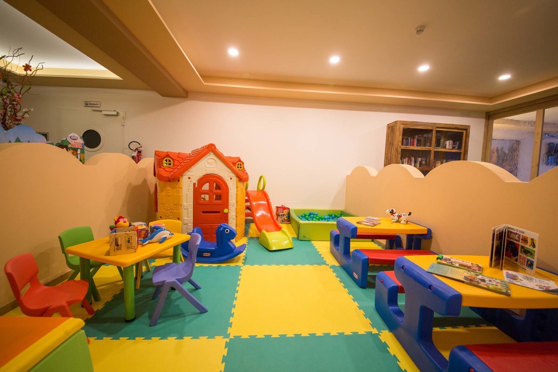 Een speelgedeelte voor kinderen met een huisje, glijbaan en foammatten.