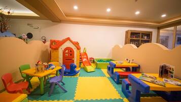 Een speelgedeelte voor kinderen met een huisje, glijbaan en foammatten.