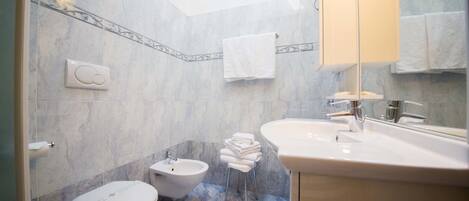A bathroom with a bidet, toilet, and sink.