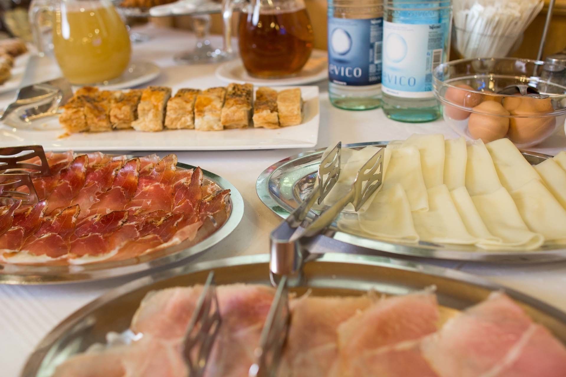 Una mesa con diversos alimentos, entre ellos fiambres, pan y una botella de agua.