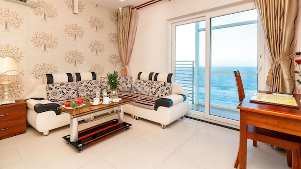 A living room with a sofa, coffee table, and a view of the sea. - Romeliess Hotel (Ho Chi Minh City)