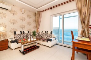 A living room with a sofa, coffee table, and a view of the sea. - Romeliess Hotel (Ho Chi Minh City)