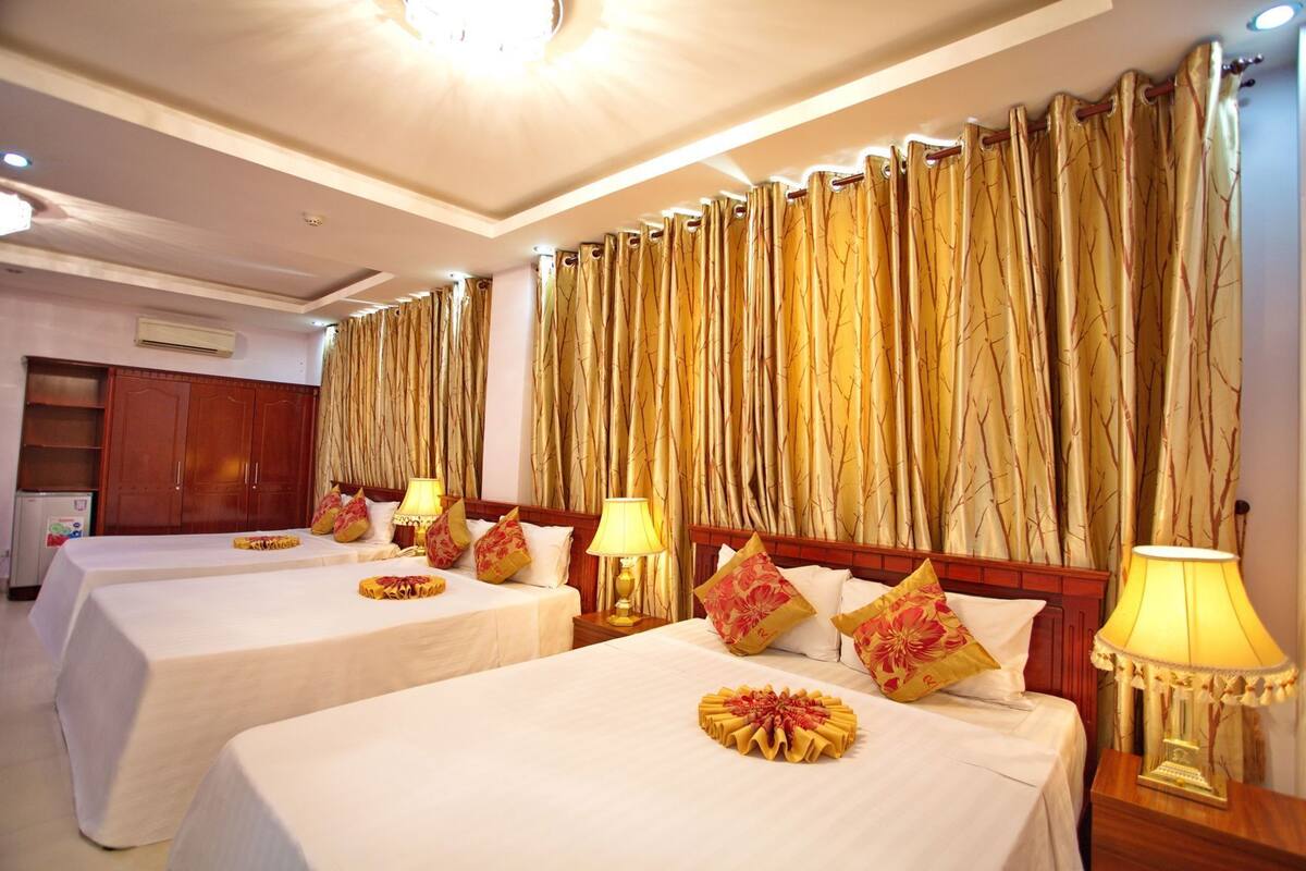 A hotel room with two beds, a wardrobe, and a large curtain with a tree pattern.