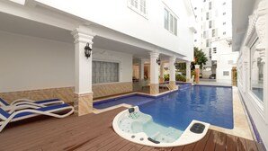 A pool area with lounge chairs, a hot tub, and a view of the surrounding buildings. - Romeliess Hotel (Ho Chi Minh City)