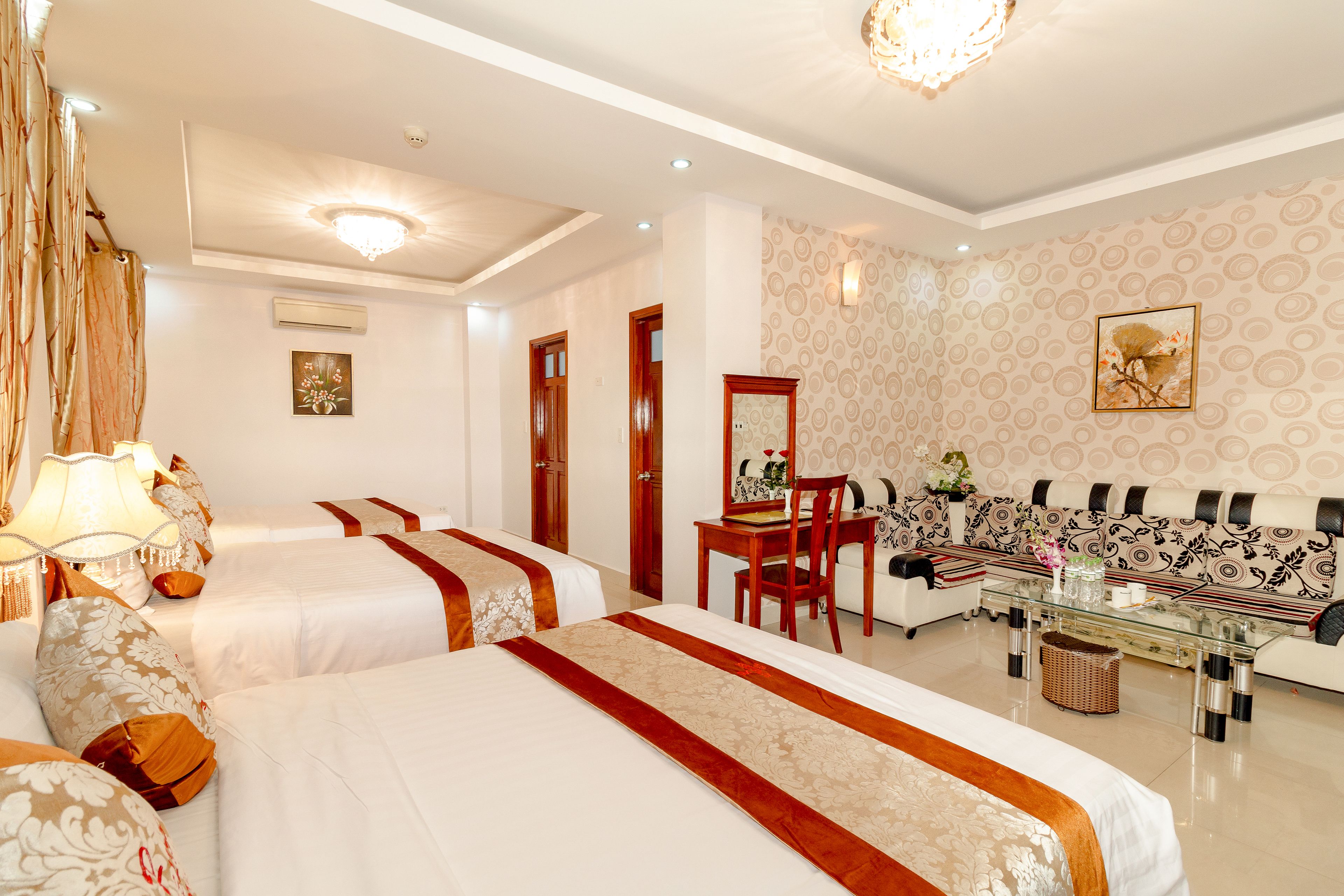 Habitación de hotel con dos camas, un sofá, una mesa de centro y un espejo.