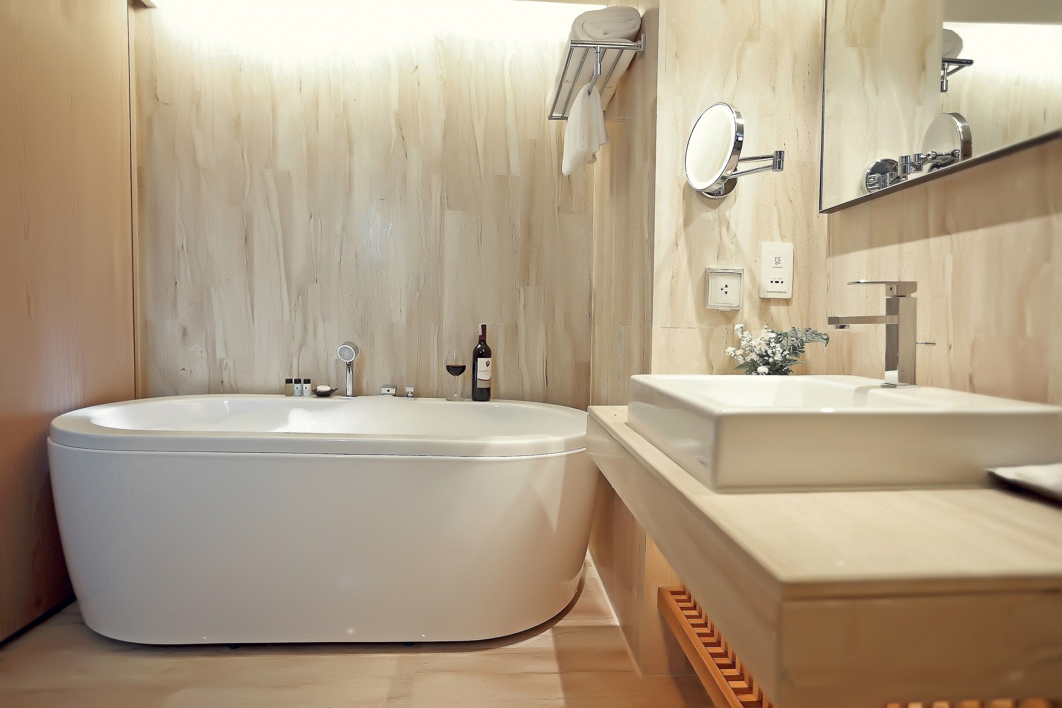 Un baño moderno con una bañera independiente, un tocador con espejo y una pared de madera.