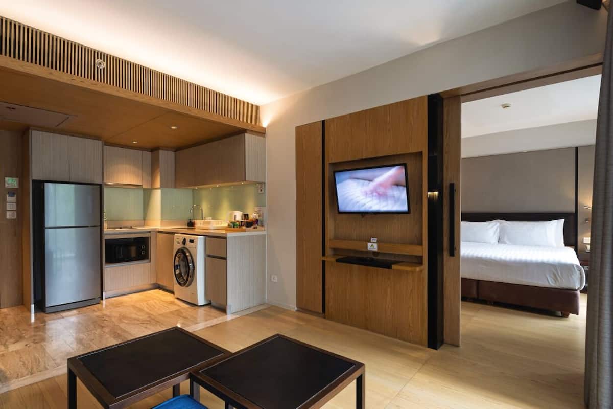 Habitación de hotel compacta con kitchenette, una cama, televisor y un pequeño rincón de descanso.