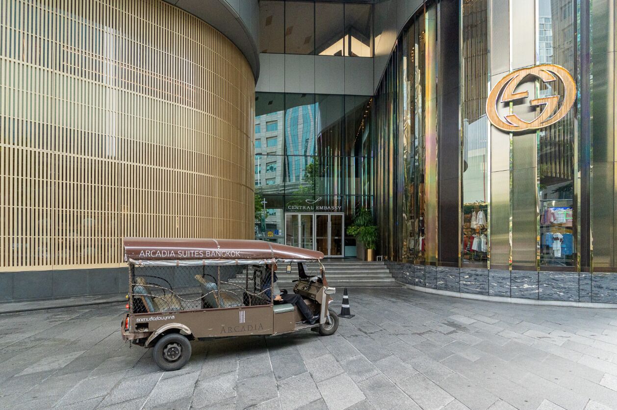 A tuk-tuk parked in front of a building with a large logo on the facade.