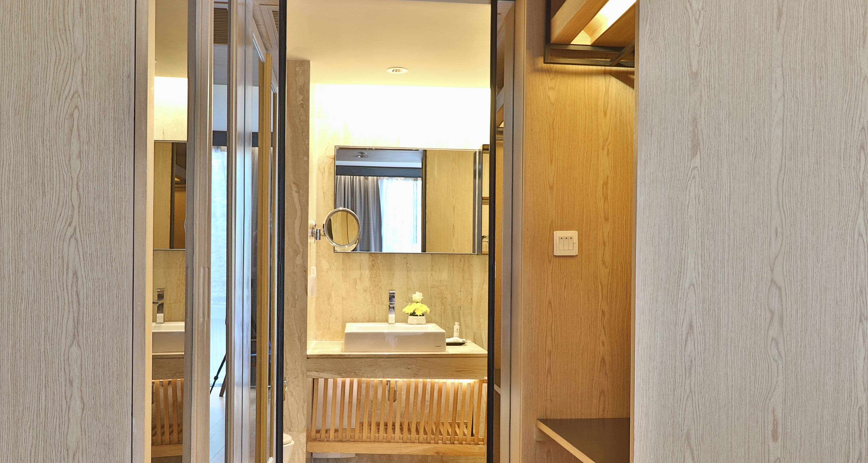 A modern bathroom with a wooden vanity, a mirror, and a sink.