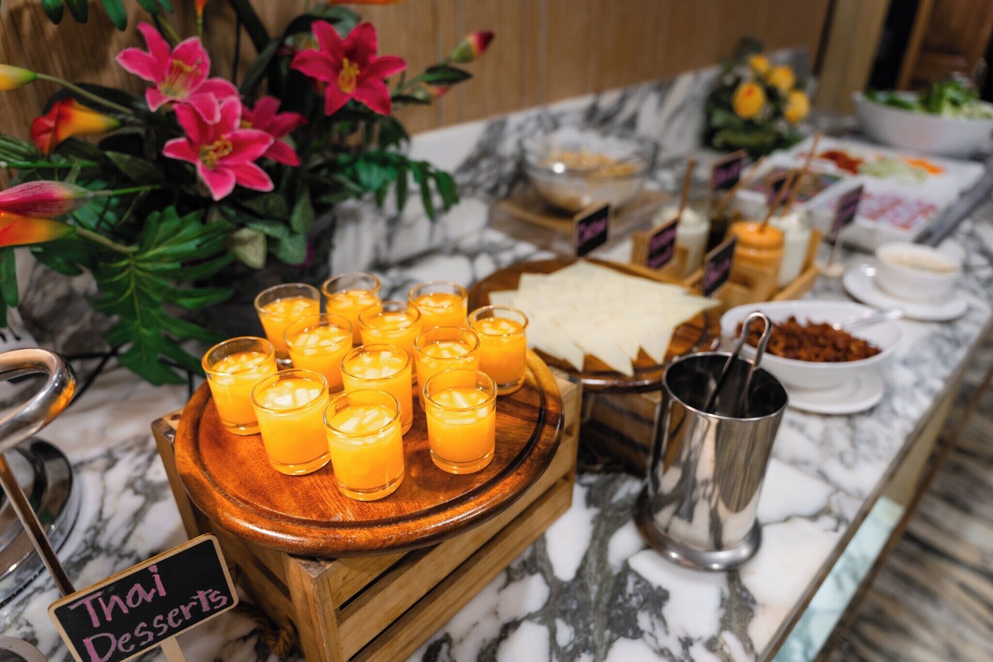 Een buffet met diverse soorten eten en een bordje met de tekst 'Thaise desserts'.