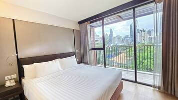 A hotel room with a large bed, a city view through floor-to-ceiling windows, and a modern design.
