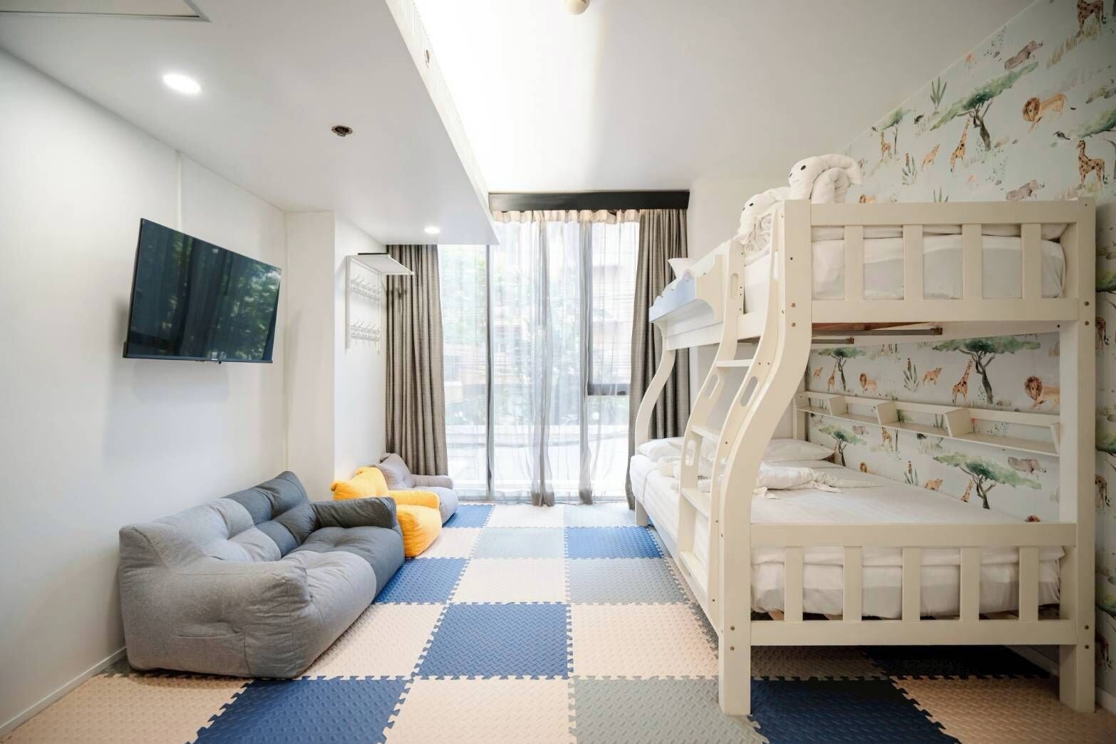 A child-friendly room with a bunk bed, a sofa, and a flat-screen TV.