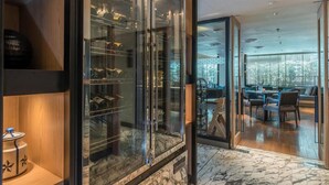 A modern interior with a glass display case, wooden shelves, and a seating area with a view.