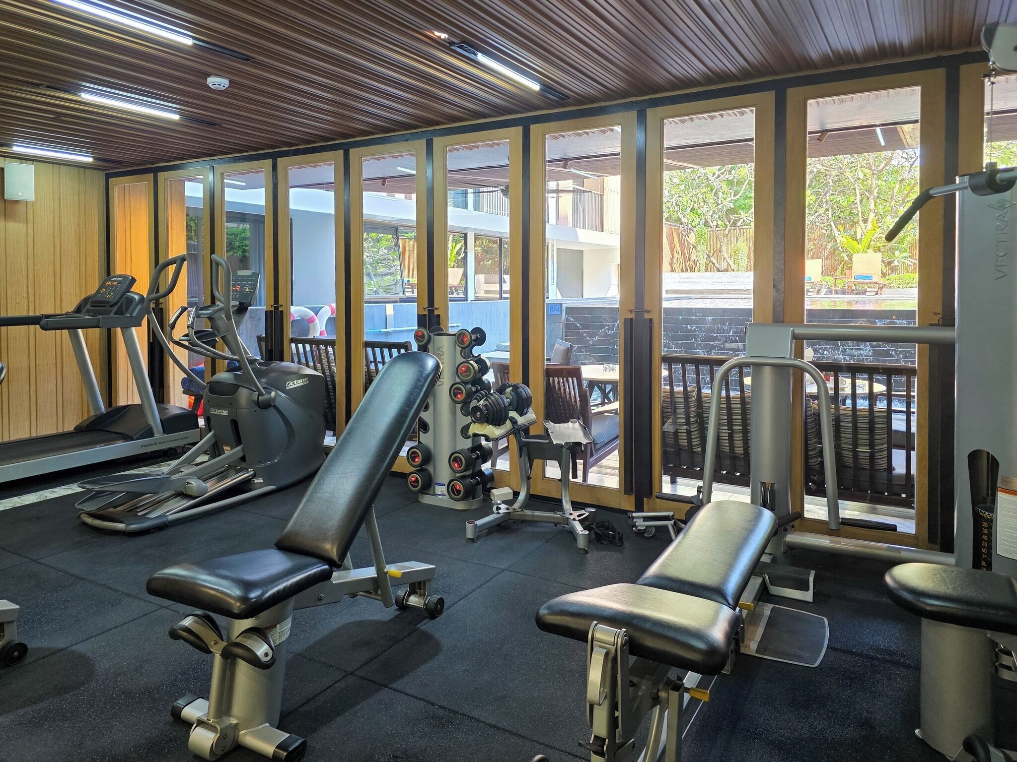 Une salle de sport équipée de matériel d’exercice, dotée de grandes fenêtres et offrant une vue sur l’extérieur.