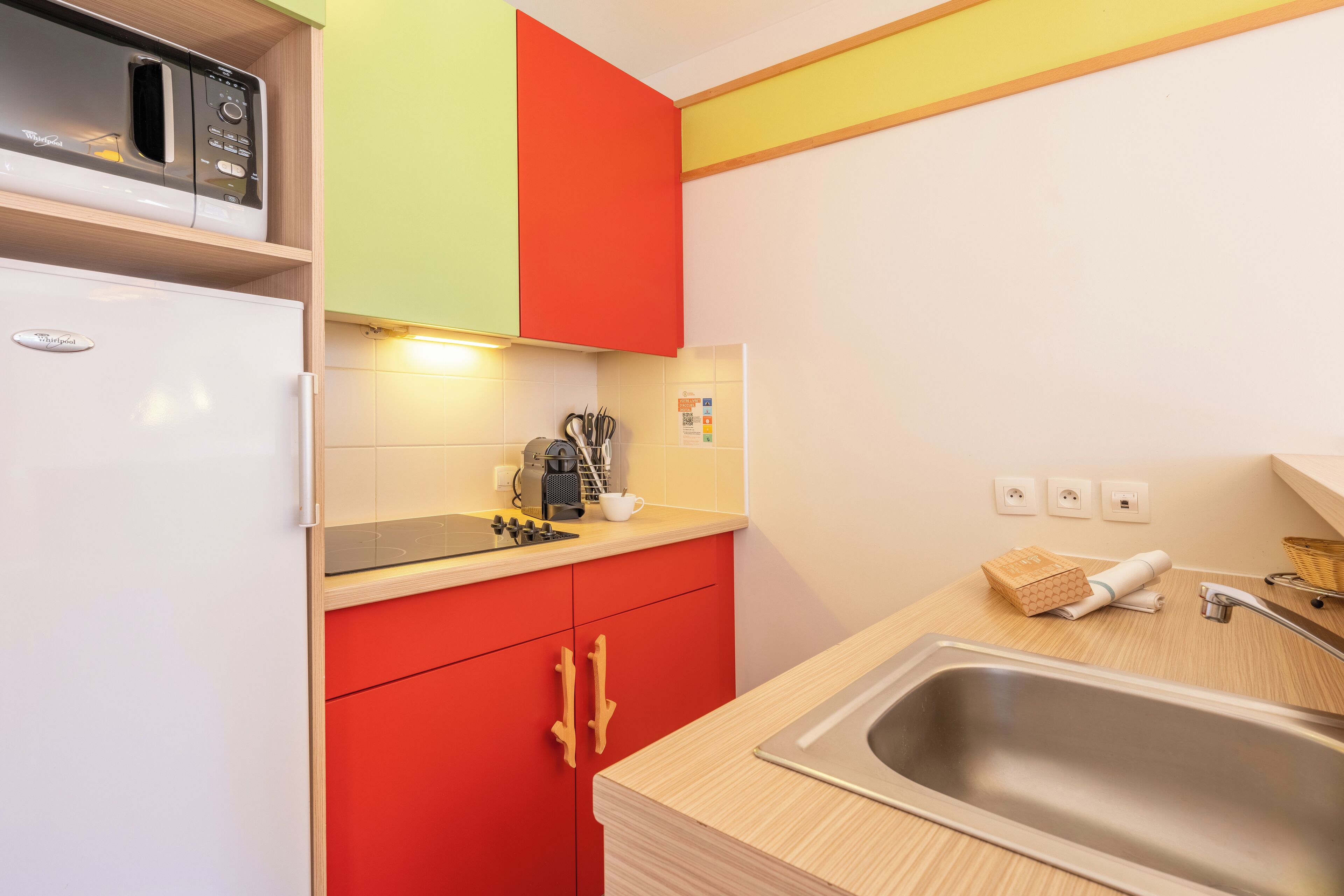 A compact kitchen with a microwave, coffee maker, and a sink.