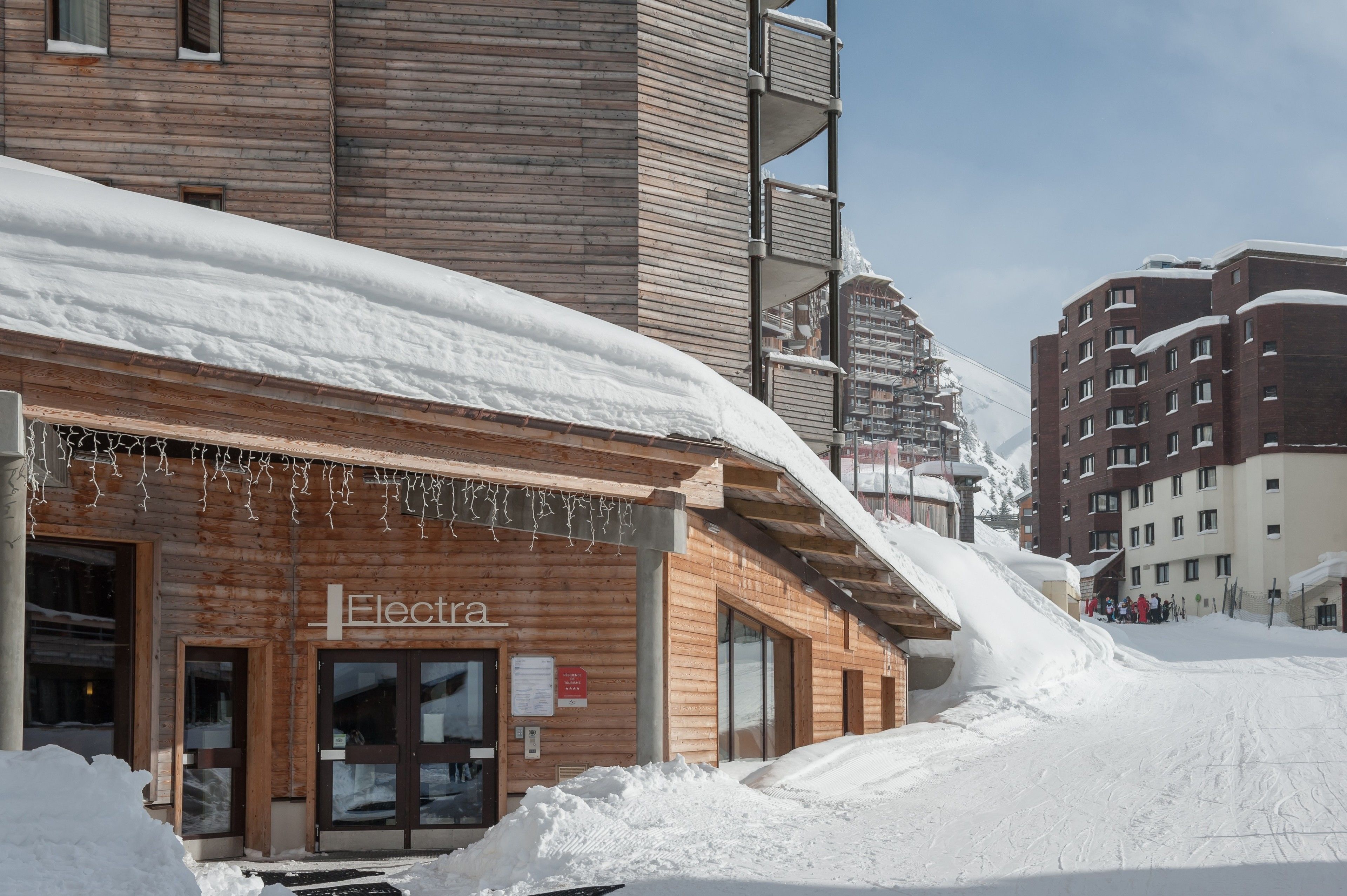 A wooden building with a sign reading "Electra" and a snow-covered slope in the background.