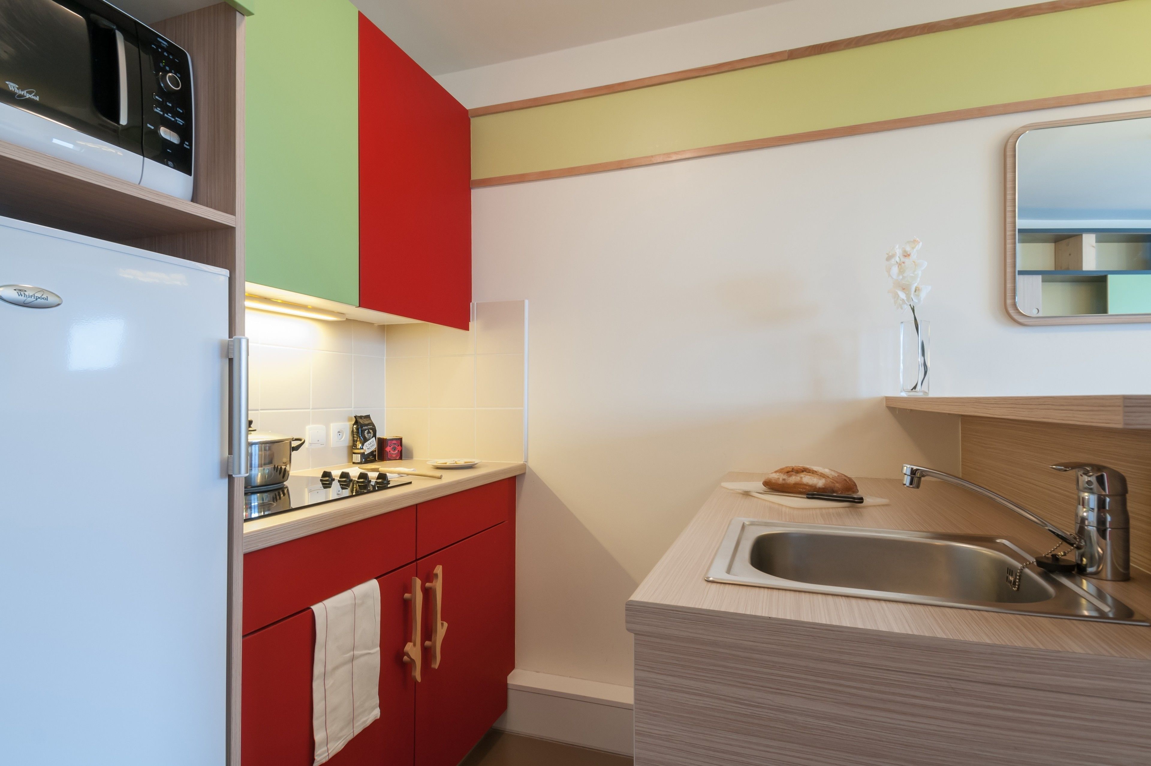 A compact kitchen with a microwave, toaster, and a sink.
