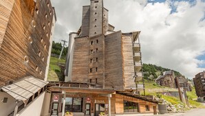 Un edificio moderno con fachada de madera, una torre destacada y un letrero que dice 'Electra'.
