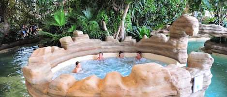 A hot tub surrounded by rock formations and lush greenery.