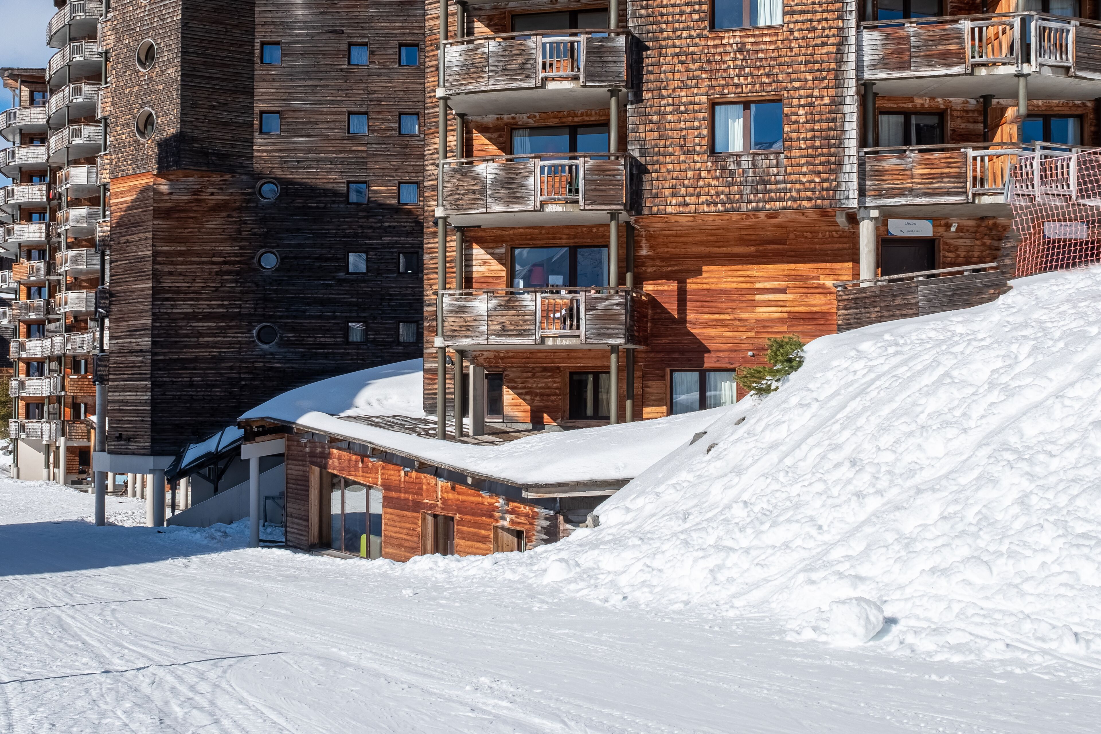 A multi-story building with balconies, a ski slope, and snow-covered surroundings.