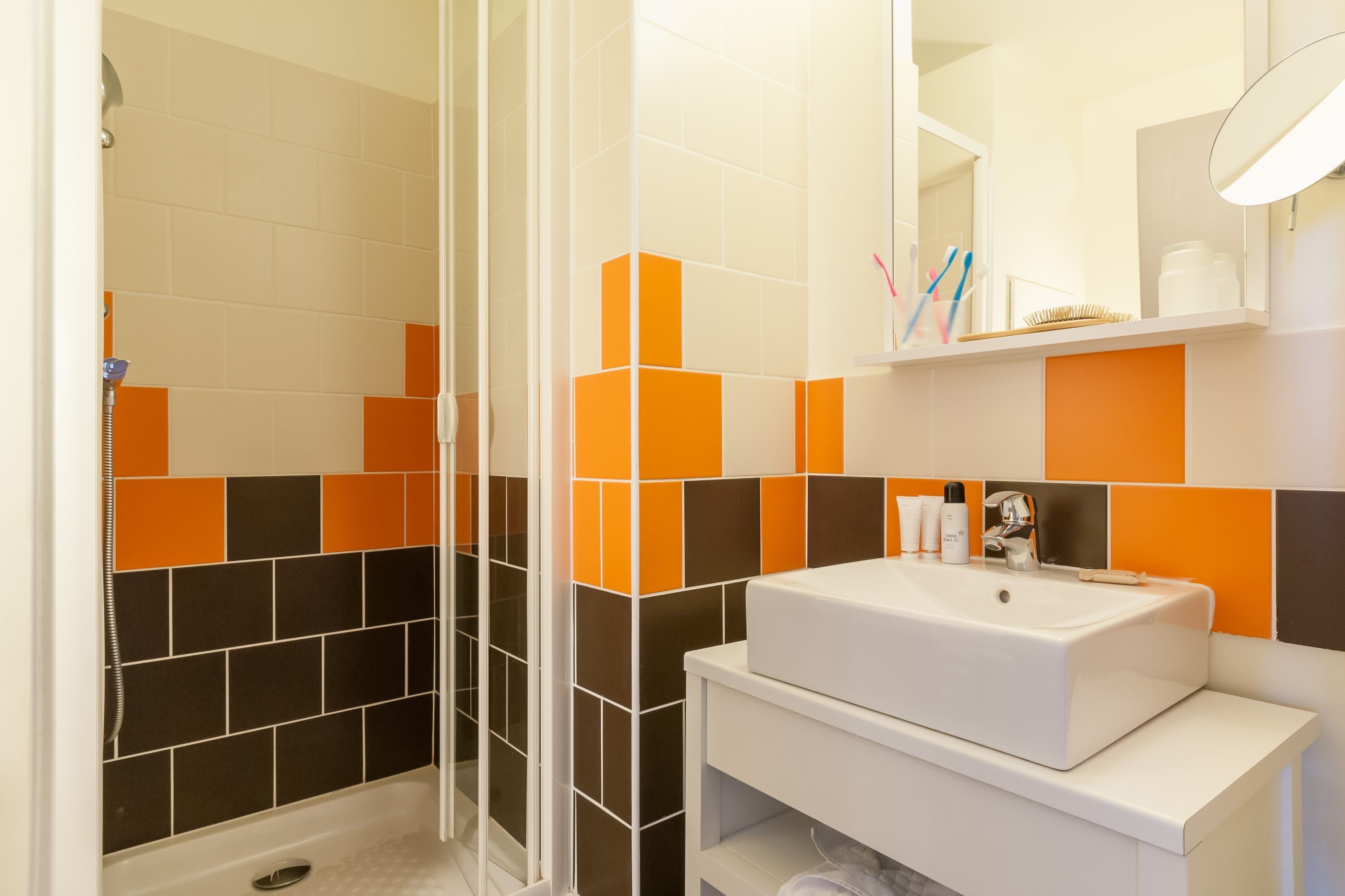 Un baño moderno con ducha, lavabo y espejo.