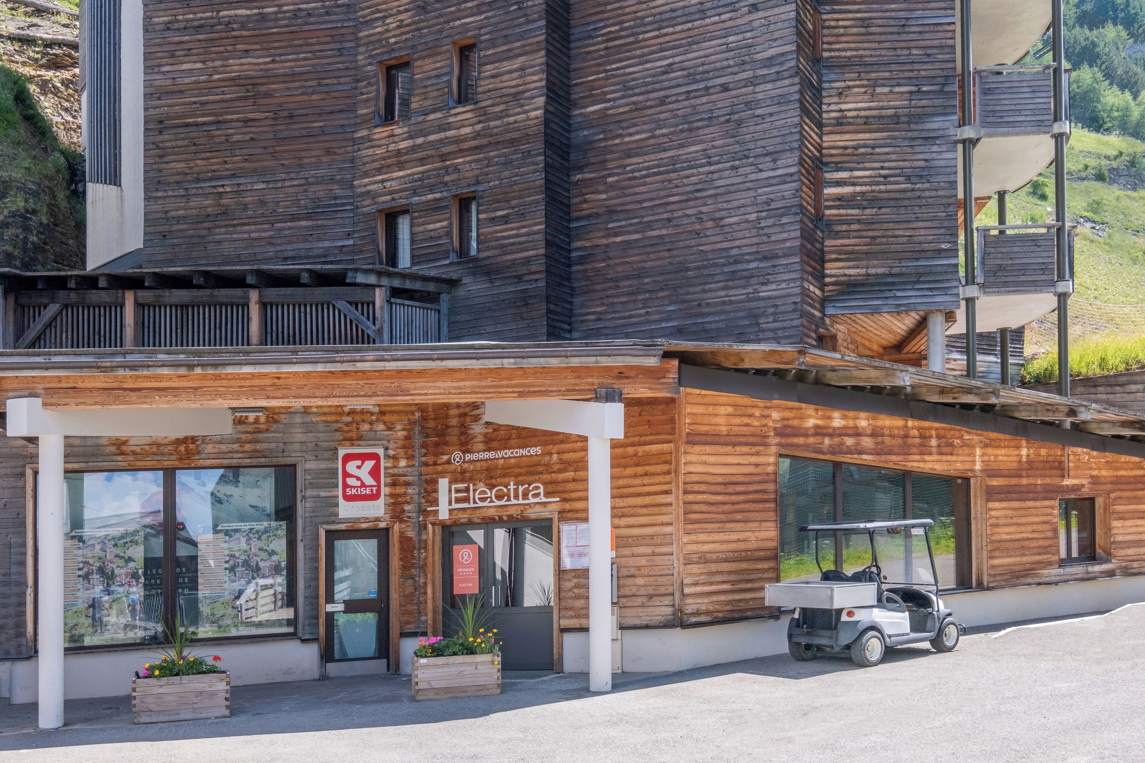A wooden building with a ski lift, a sign for 'Electra,' and a golf cart parked outside.