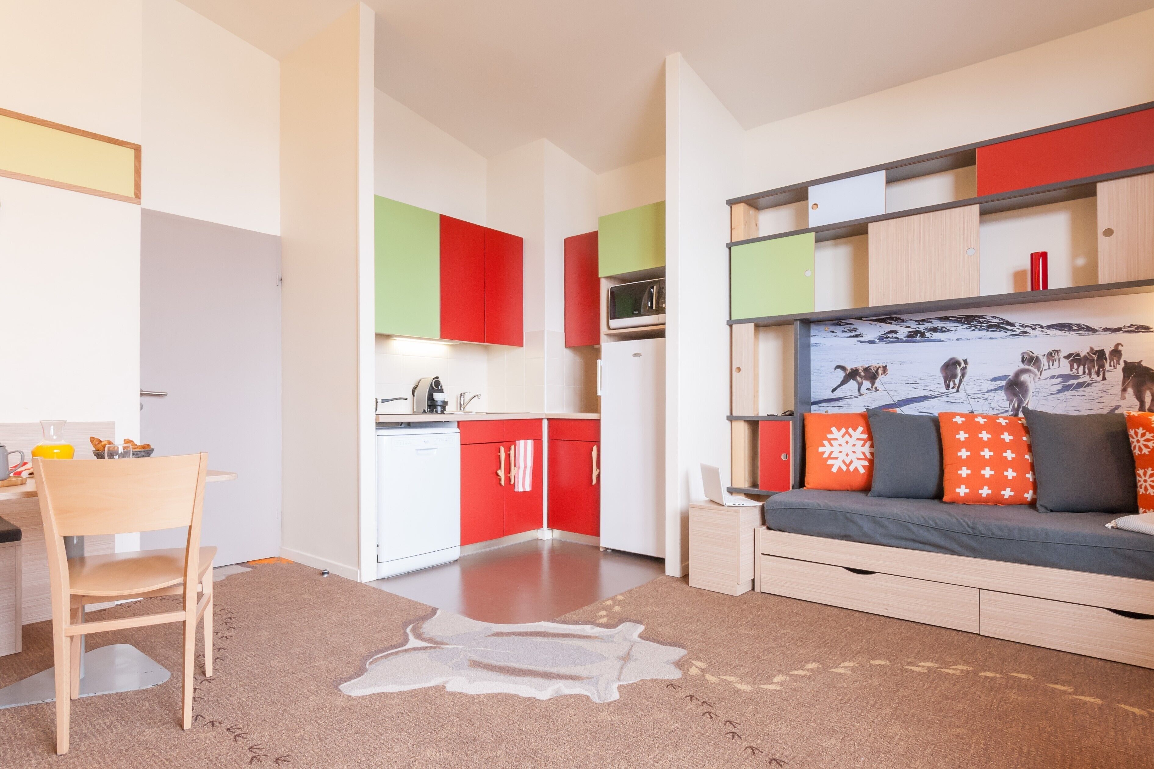 Eine moderne Wohnung mit Küche, Essbereich und Wohnzimmer, inklusive Sofa und Wand-Fernseher.