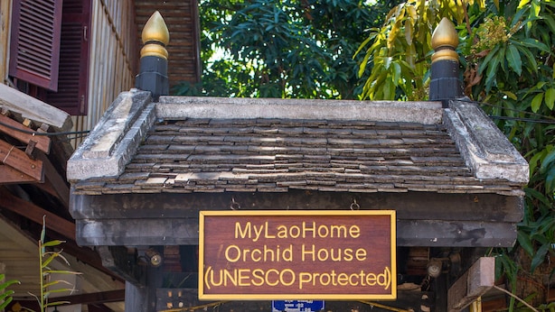 Ein Weg führt zu einem Haus, dessen Schild darauf hinweist, dass es sich um ein geschütztes Orchideenhaus der UNESCO handelt.