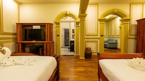 Ein Hotelzimmer mit zwei Betten, einem Fernseher, einem Holzschrank und einem Spiegel.