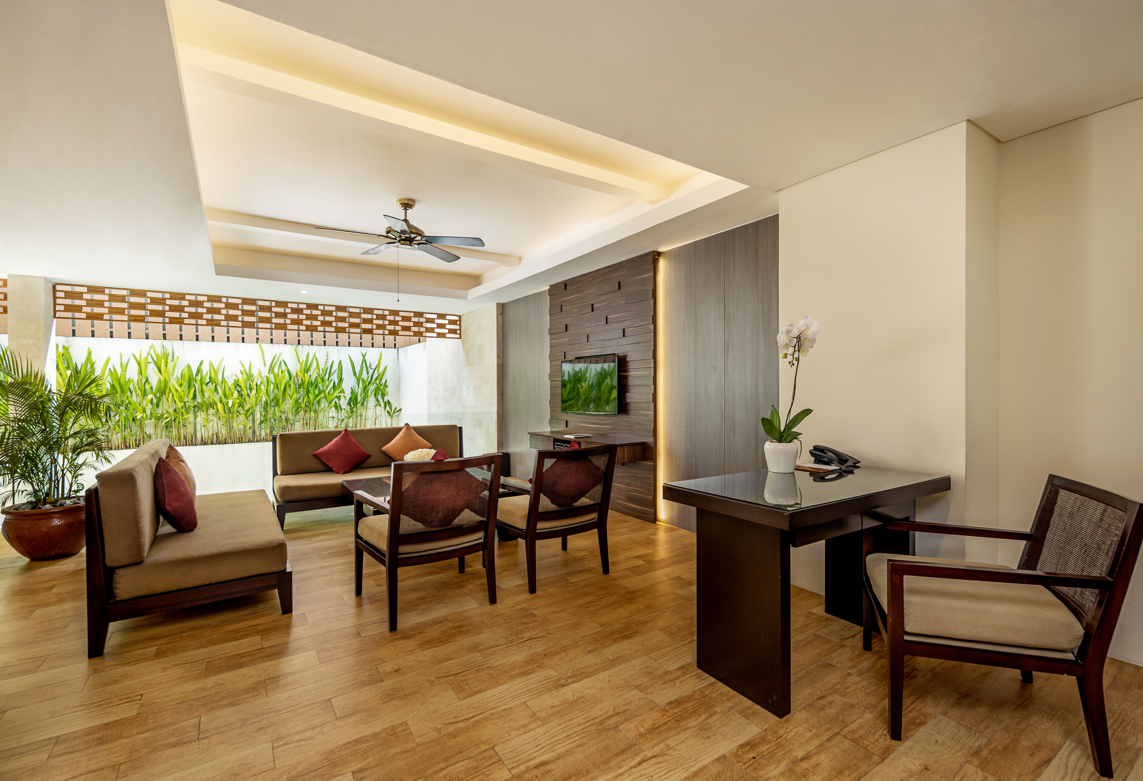 A modern living room with a sofa, chairs, a dining table, and a ceiling fan.