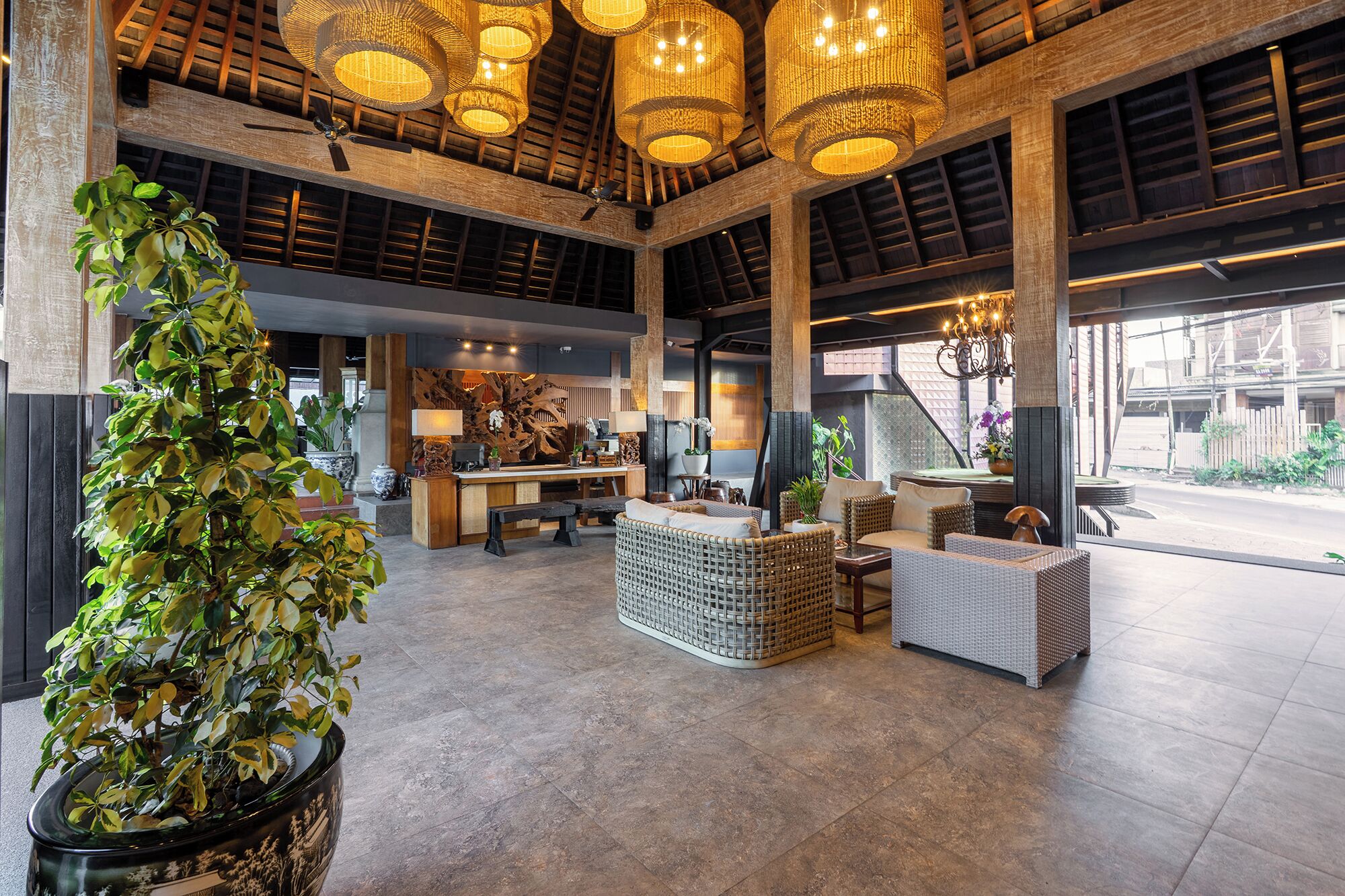 A spacious lobby with high ceilings, large windows, and a central seating area with wicker furniture.