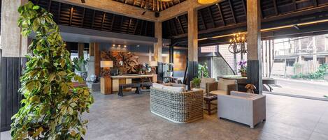 A spacious lobby with high ceilings, large windows, and a central seating area with wicker furniture.