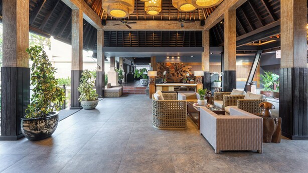 A spacious lobby with high ceilings, exposed wooden beams, and a central seating area with wicker furniture. - Villa Kayu Raja (Seminyak)