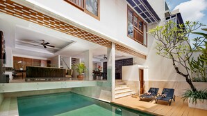 A modern house with a swimming pool, outdoor seating, and a staircase leading to a balcony. - Villa Kayu Raja (Seminyak)