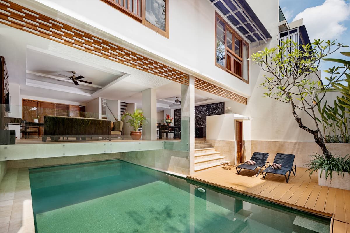 A modern house with a swimming pool, outdoor seating, and a staircase leading to a balcony.