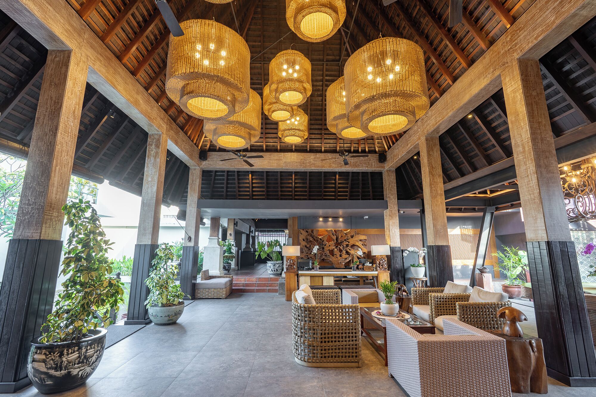 A spacious lobby with high ceilings, multiple hanging wicker chandeliers, and a central seating area with wicker furniture.