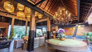 A spacious lobby with high ceilings, exposed wooden beams, and a central round table with a floral arrangement. - Villa Kayu Raja (Seminyak)