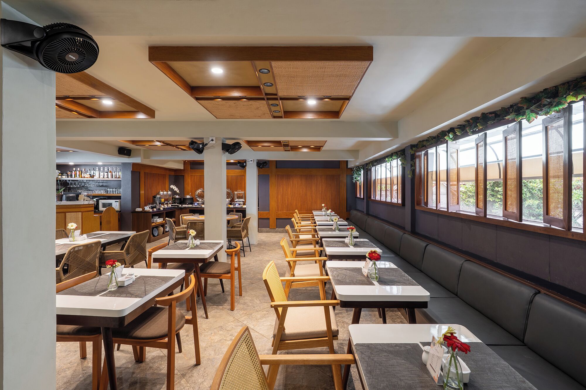 A restaurant with a long counter, booths, and a bar area.