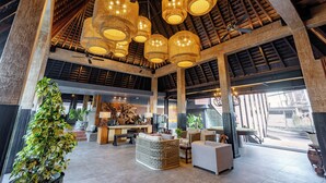 A spacious lobby with high ceilings, large wicker furniture, and a central reception desk. - Villa Kayu Raja (Seminyak)