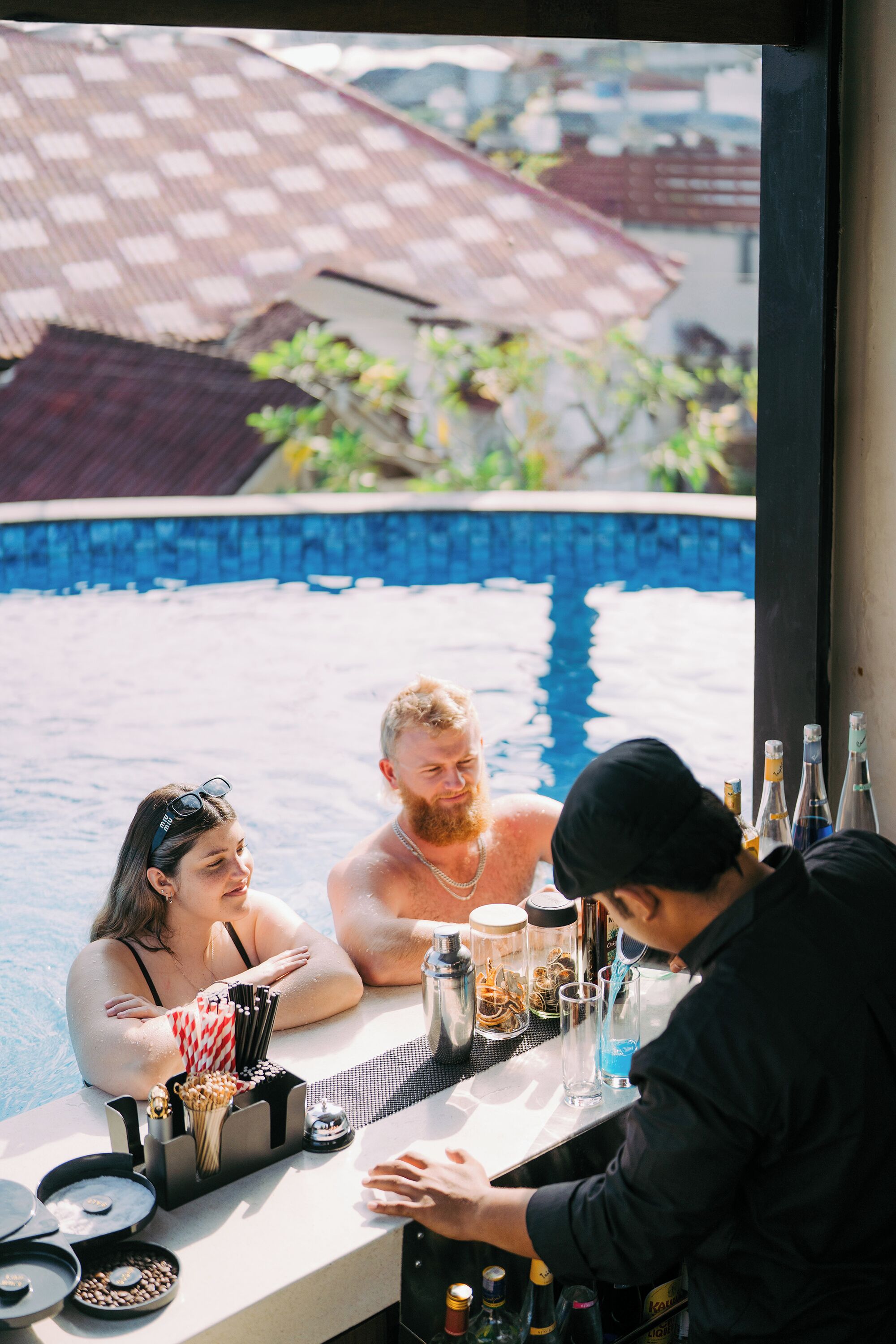 A bar area with a pool view, bar stools, and a bartender.