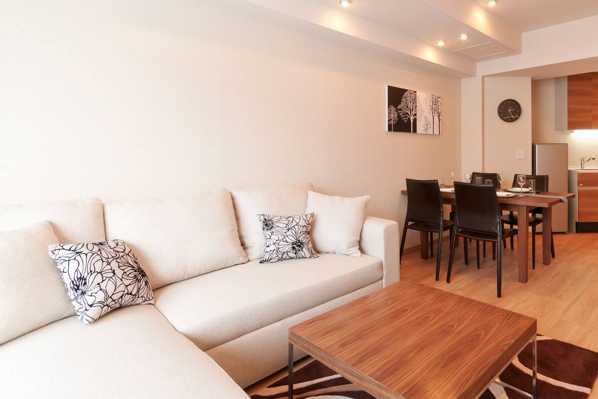 A modern living room with a sofa, coffee table, and dining area.