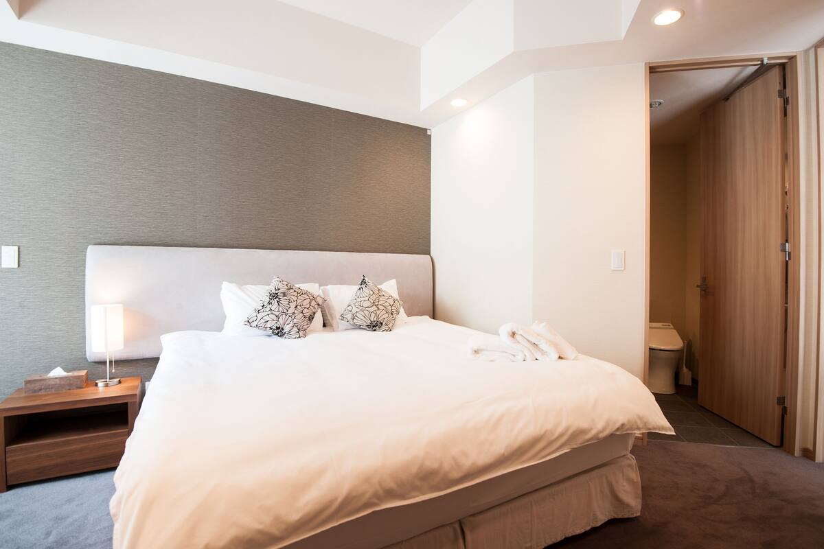 A neatly made bed with a white headboard, a bedside lamp, and a telephone on the nightstand.