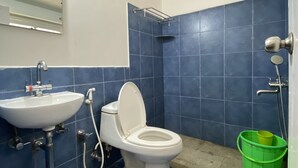 A bathroom with a white sink, toilet, and shower. Blue tiles cover the walls and floor. - I - India (Coonoor)