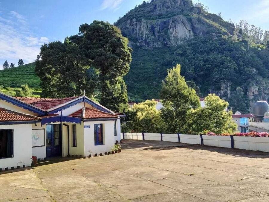 A building with a tiled roof and a white facade, situated in a courtyard with a view of a mountainous landscape.