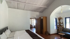 A bedroom with a large bed, a wooden floor, a wardrobe, and a seating area with a table and chairs. - I - India (Coonoor)